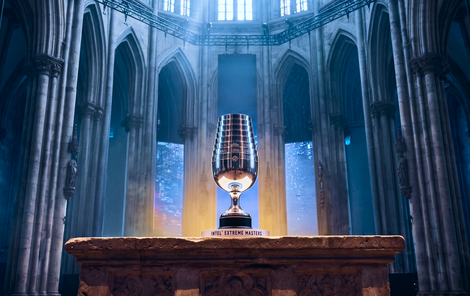 The IEM trophy displayed on a wooden pedestal inside a grand cathedral interior