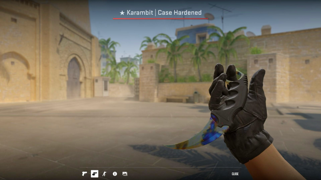 Karambit Case Hardened Blue Gem knife inspect view in a sandy courtyard CS2 map setting